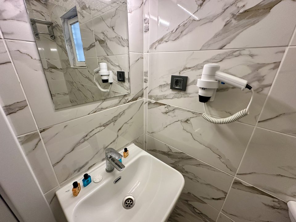 Banyoda lavabo, ayna ve saç kurutma makinesi.
