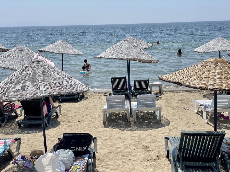 Deniz ve plajdaki hasır şemsiyeler.