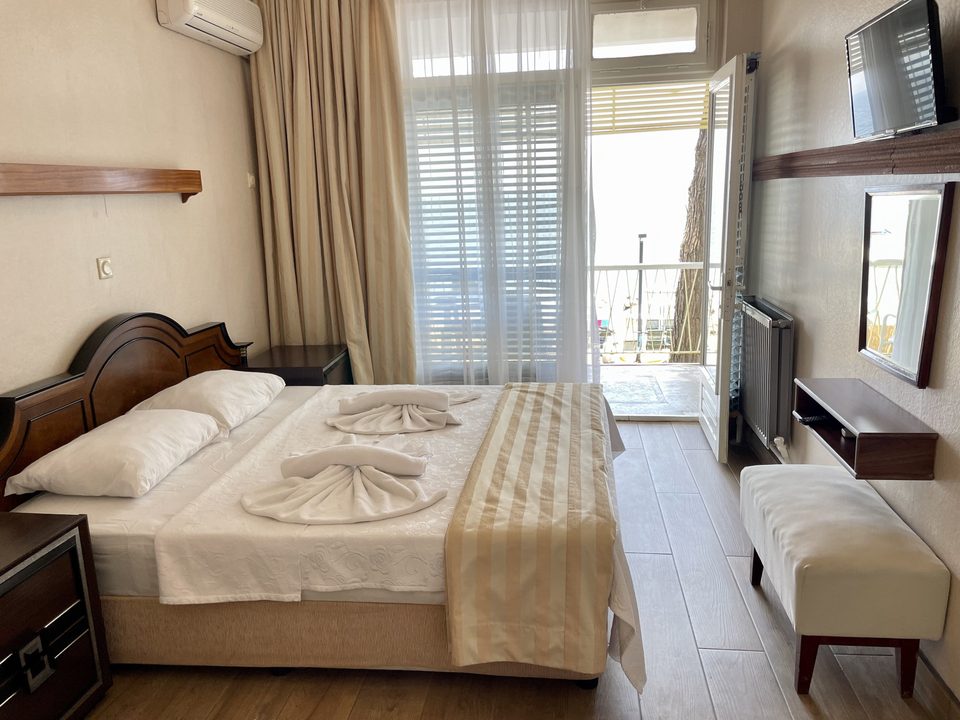 Çift kişilik yatak, televizyon ve balkon kapısı bulunan oda.